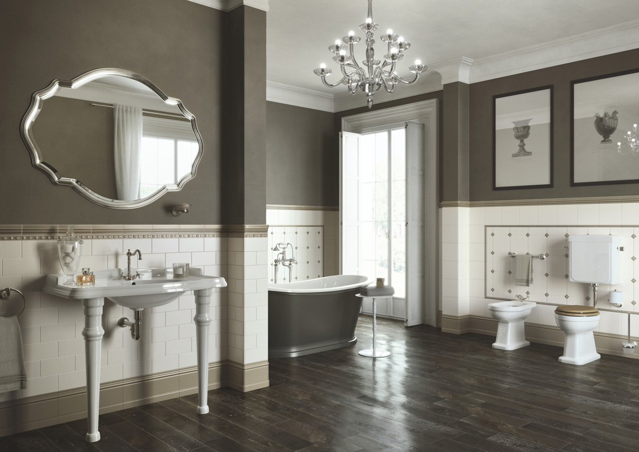 Prostorná koupelna s obklady Ceramiche Grazia Amarcord do poloviny stěn, tmavě hnědými stěnami nahoře a tmavou dřevěnou podlahou. Místnost zahrnuje volně stojící vanu, umyvadlo s chromovými kohoutky a oválné zrcadlo v ozdobném rámu.