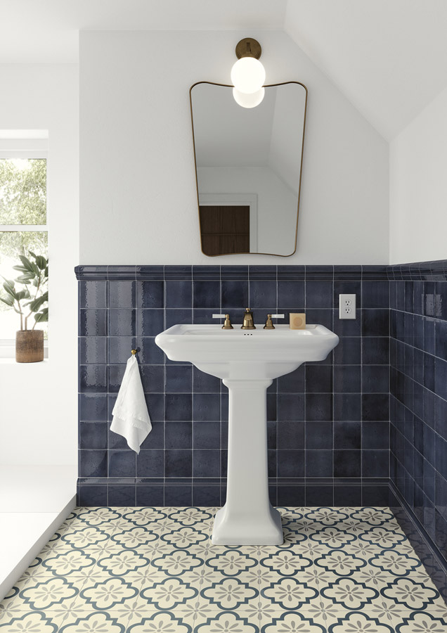 Elegantní koupelna s tmavě modrými lesklými obklady Ceramiche Grazia Shades of Art, bílým umyvadlem na podstavci a zlatými armaturami.